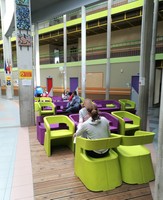 Photo du hall du collège avec des élèves assis sur les fauteuils design vert et violet