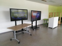Photo montrant l'un des murs de la salle Lab après le projet, dégagé avec seulement 2 écrans numériques mobiles