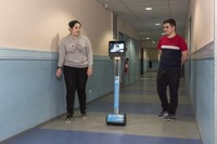 Photo montrant deux lycéens qui marchent dans un couloir avec le robot de téléprésence.