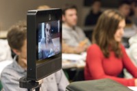 Photo montrant une classe de lycéens en train d'écouter leur professeur et au premier plan un élève apparait sur l'écran du robot de téléprésence